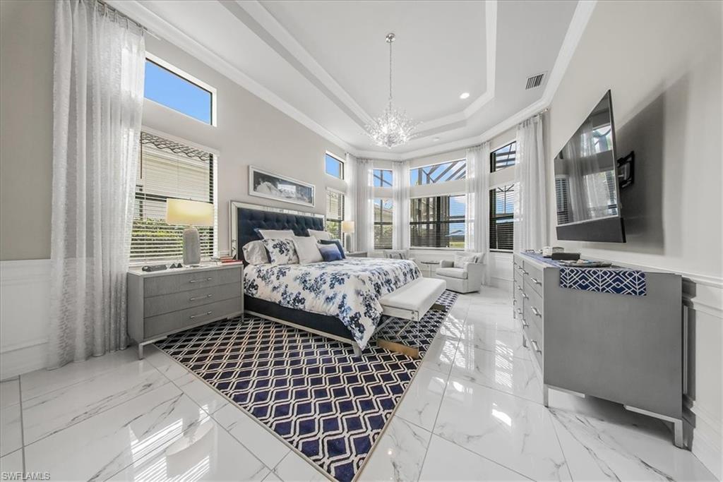 4616 Azalea Drive Naples, FL 34119 - Photo 14 of 44 Bedroom featuring a tray ceiling, multiple windows, light marble finish floors, crown molding, and a chandelier