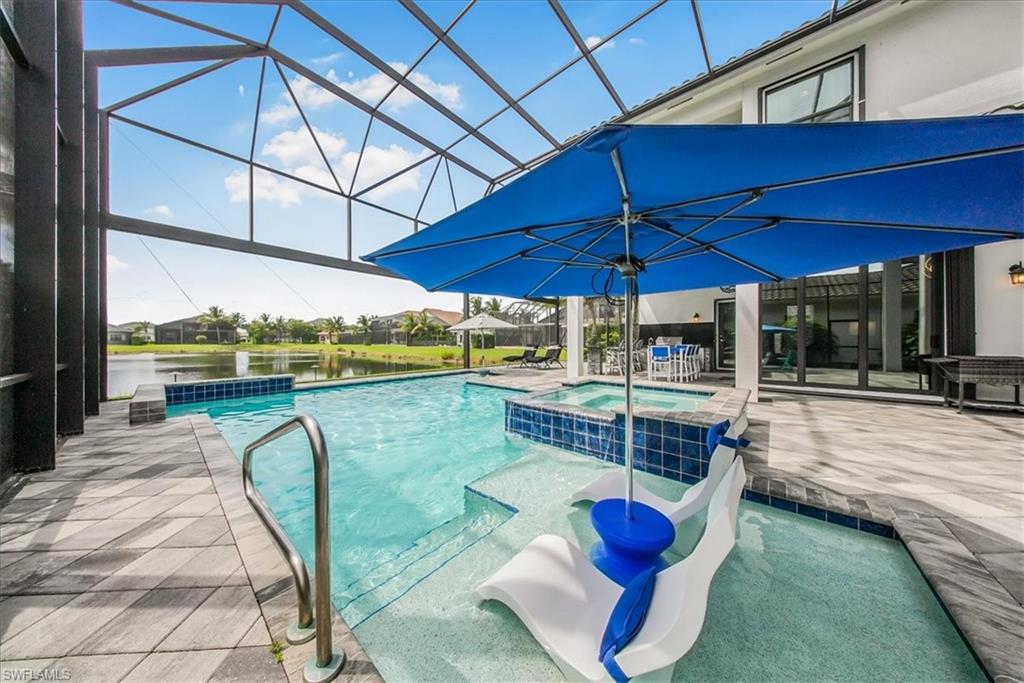 4616 Azalea Drive Naples, FL 34119 - Photo 28 of 44 View of swimming pool with a pool with connected hot tub, a patio, glass enclosure, and a water view