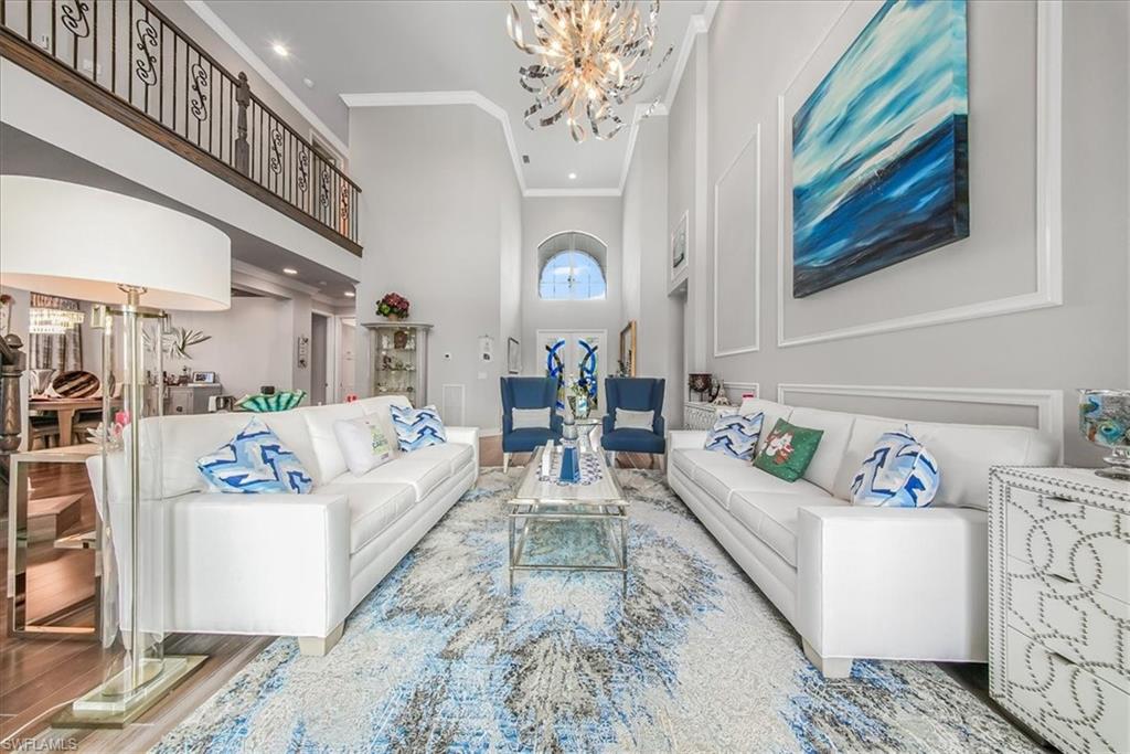 4616 Azalea Drive Naples, FL 34119 - Photo 5 of 44 Living area featuring a towering ceiling, a chandelier, crown molding, and wood finished floors