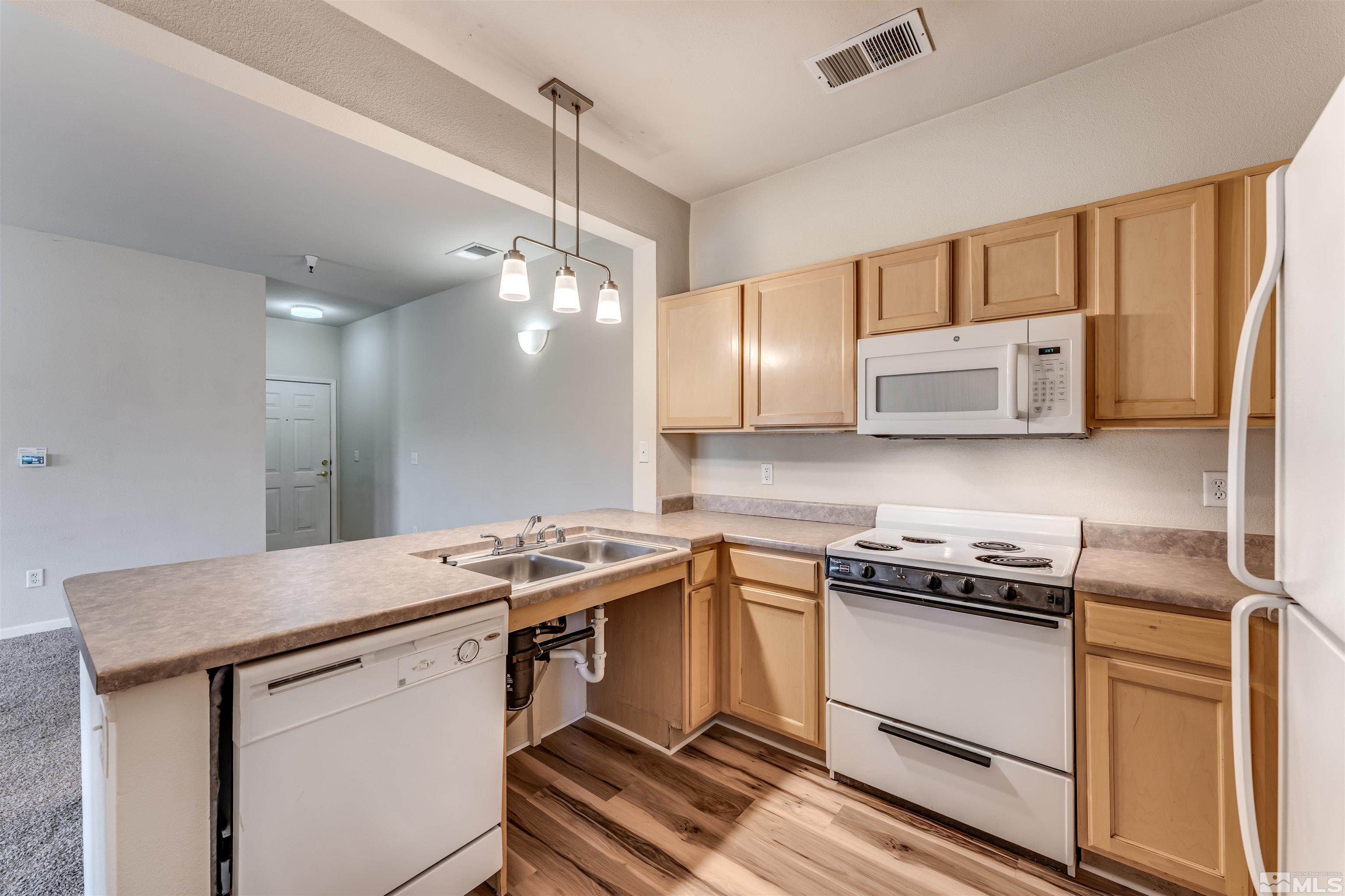 200 Talus Way, Unit 312 Reno, NV 89503 - Photo 12 of 33 a kitchen with stainless steel appliances a stove a microwave and white cabinets