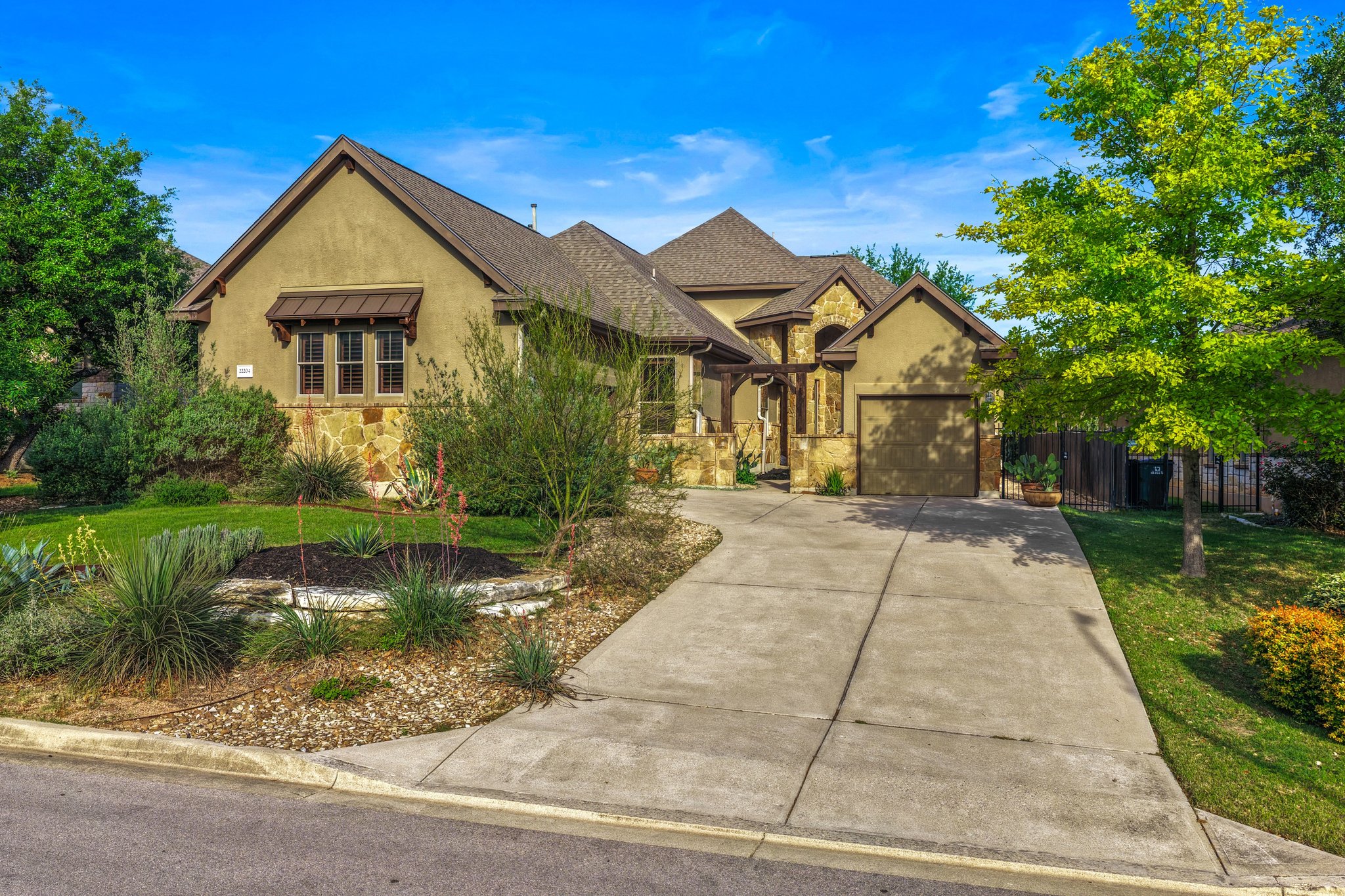 View of front facade featuring stucco siding, concrete driveway, stone siding, a standing seam roof, and a garage