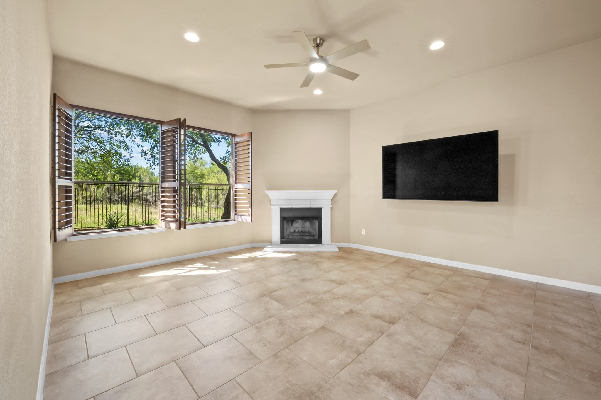 22204 Red Yucca Road Spicewood, TX 78669 - Photo 10 of 34 Unfurnished living room with a ceiling fan, a fireplace with raised hearth, and recessed lighting