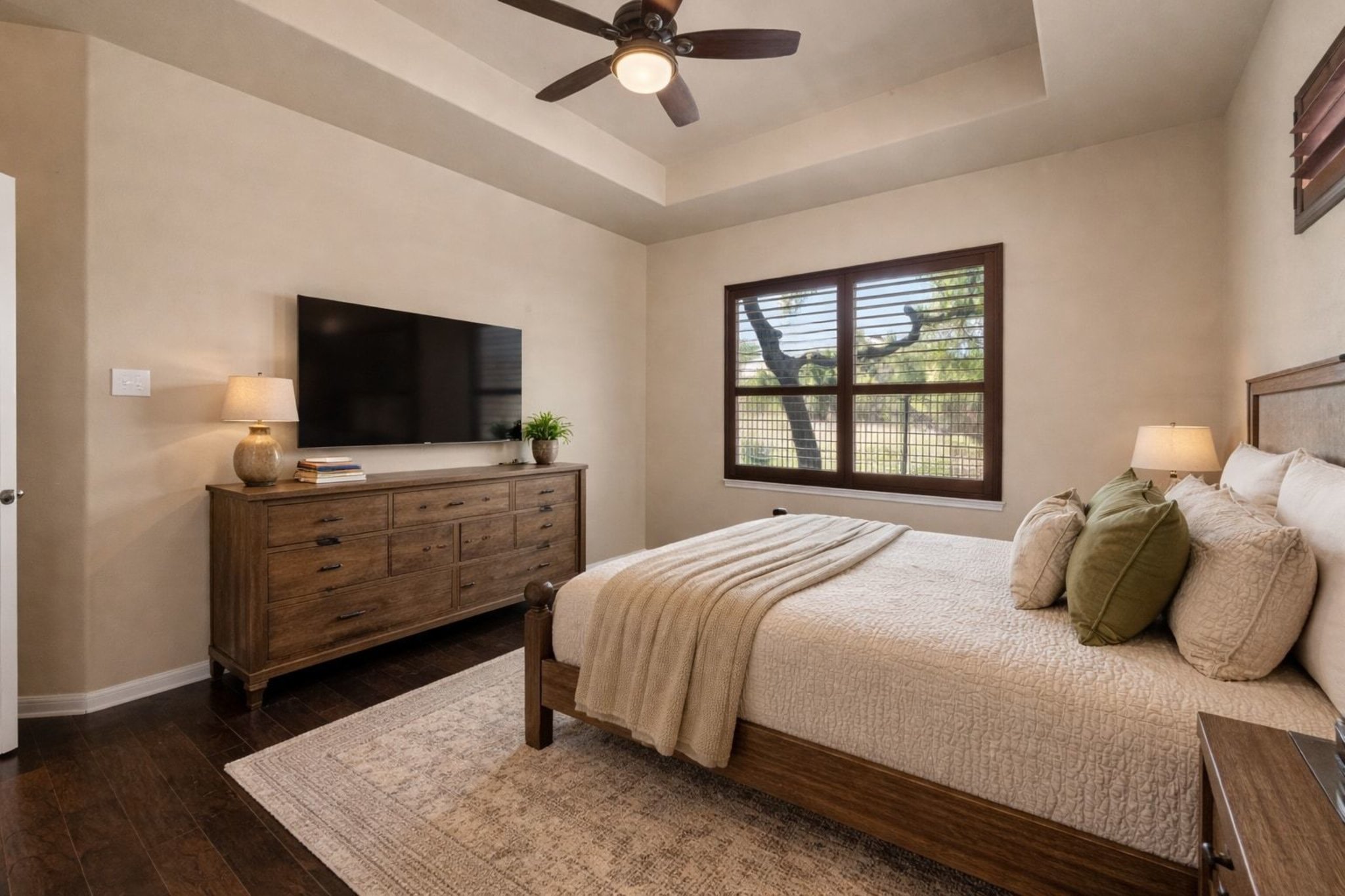 22204 Red Yucca Road Spicewood, TX 78669 - Photo 17 of 34 Bedroom featuring dark wood-style floors, a ceiling fan, and a raised ceiling