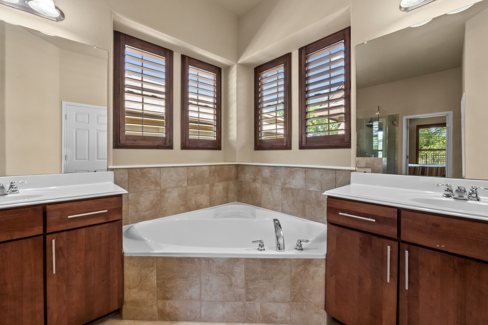 22204 Red Yucca Road Spicewood, TX 78669 - Photo 21 of 34 Bathroom featuring a bath, two vanities, and a shower stall
