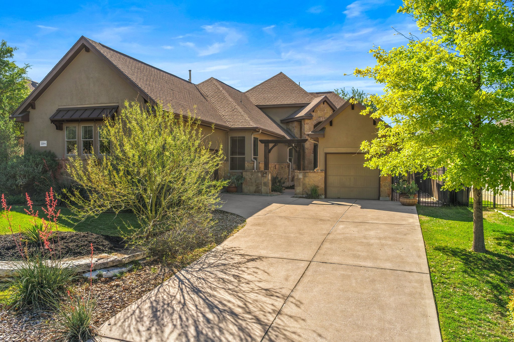 22204 Red Yucca Road Spicewood, TX 78669 - Photo 3 of 34 View of front of home with stucco siding, driveway, an attached garage, and stone siding