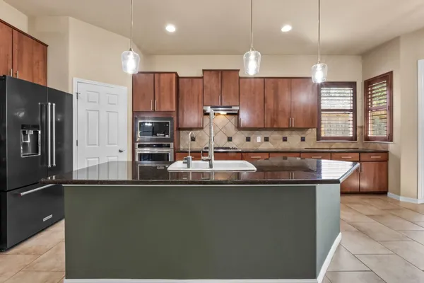 a kitchen with stainless steel appliances granite countertop a stove a sink a refrigerator and a microwave