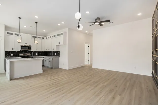 a kitchen with stainless steel appliances granite countertop a stove a sink and white cabinets with wooden floor