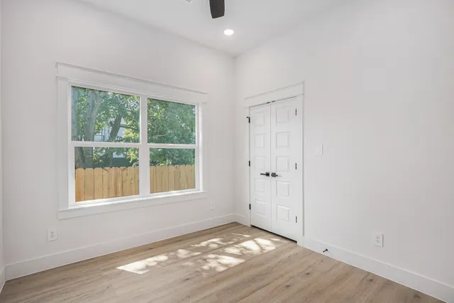 an empty room with wooden floor and windows