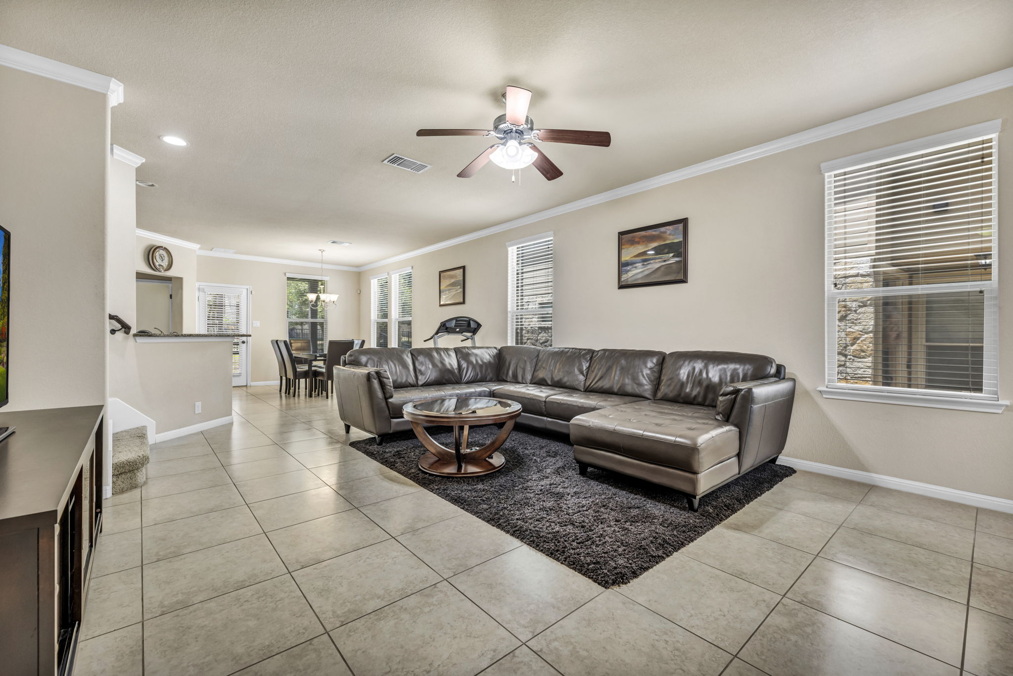 Living room with ornamental molding, ceiling fan, and light tile patterned floors