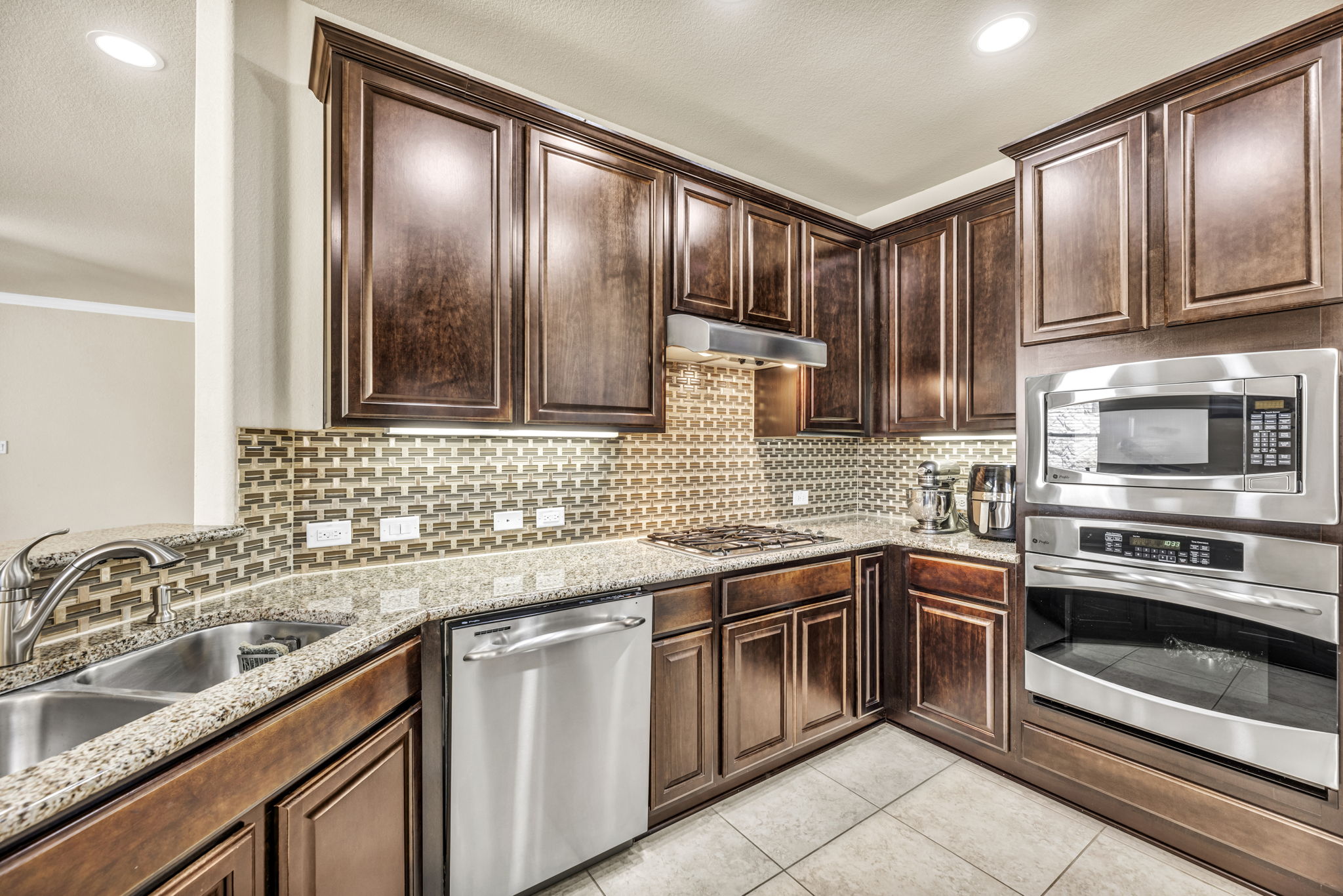 7320 Bandera Ranch Trail, Unit B Austin, TX 78750 - Photo 8 of 27 Kitchen with stainless steel appliances, dark wood finish cabinetry, light stone countertops, recessed lighting, and light tile patterned floors