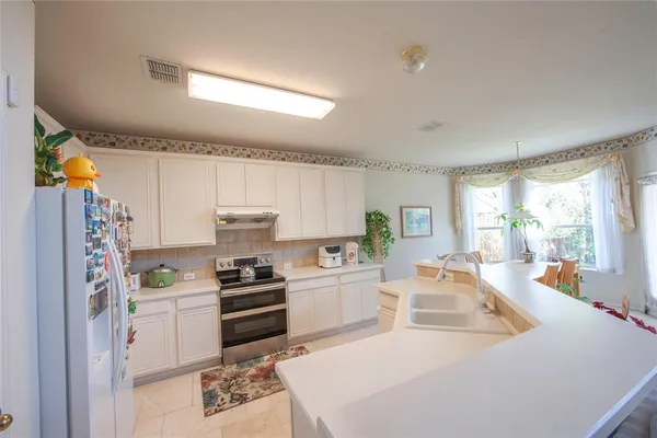 a kitchen with a refrigerator a stove a sink and a dining table with wooden floor