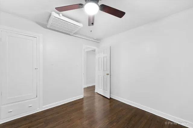 an empty room with wooden floor ceiling fan and window