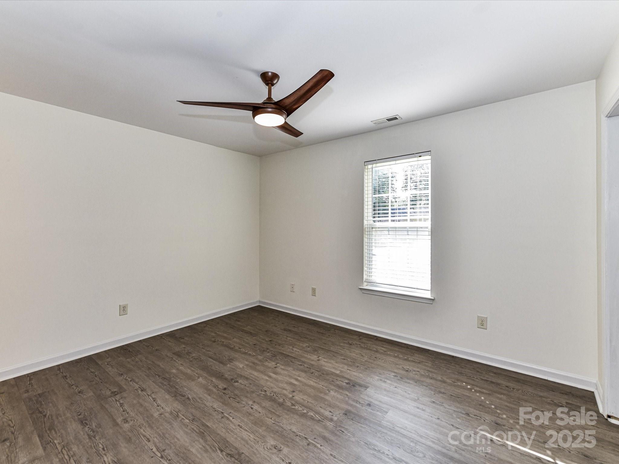 12224 Lullingstone Road Pineville, NC 28134 - Photo 11 of 26 an empty room with wooden floor ceiling fan and windows