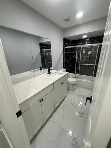a bathroom with a sink a toilet a mirror and shower