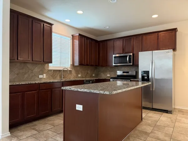 a kitchen with granite countertop wooden cabinets a refrigerator and a sink