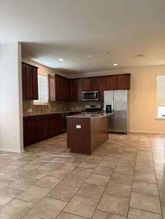 a large kitchen with granite countertop a stove a sink dishwasher and a refrigerator