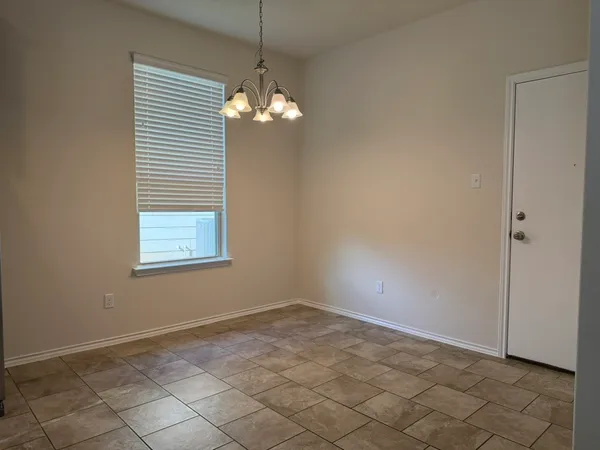 an empty room with chandelier fan and windows