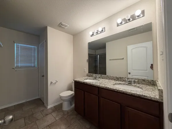 a bathroom with a granite countertop sink a toilet and a mirror