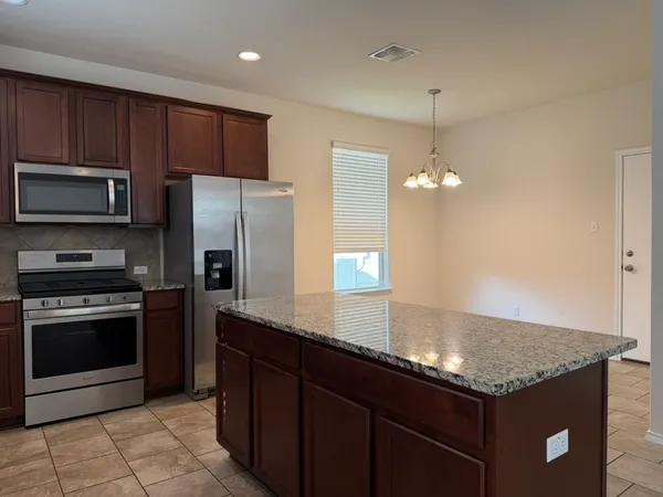 a kitchen with stainless steel appliances granite countertop a sink a stove a refrigerator and a microwave