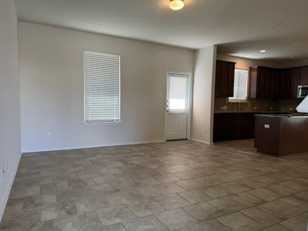 an empty room with kitchen view and window