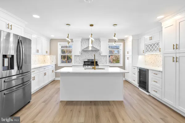 a kitchen with stainless steel appliances white cabinets a sink a stove a refrigerator and wooden floor