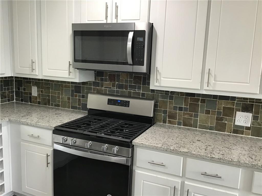 6184 Geiger Street Northwest Covington, GA 30014 - Photo 6 of 16 a kitchen with granite countertop white cabinets and appliances