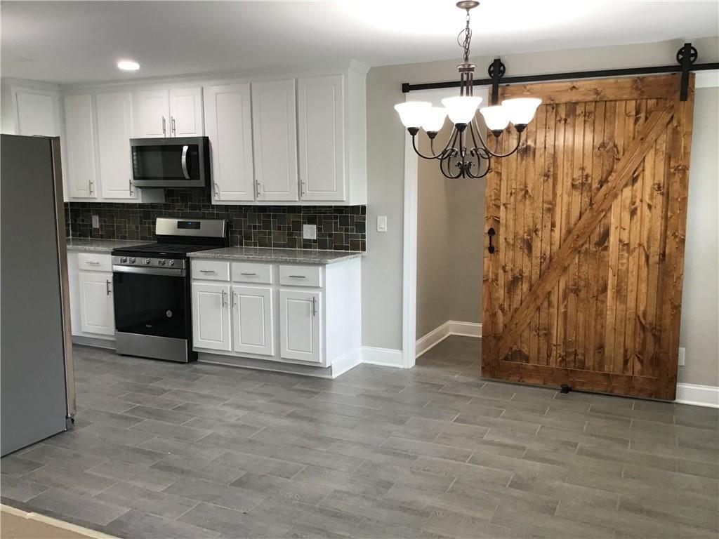 6184 Geiger Street Northwest Covington, GA 30014 - Photo 7 of 16 a kitchen with stainless steel appliances granite countertop a refrigerator and a stove top oven