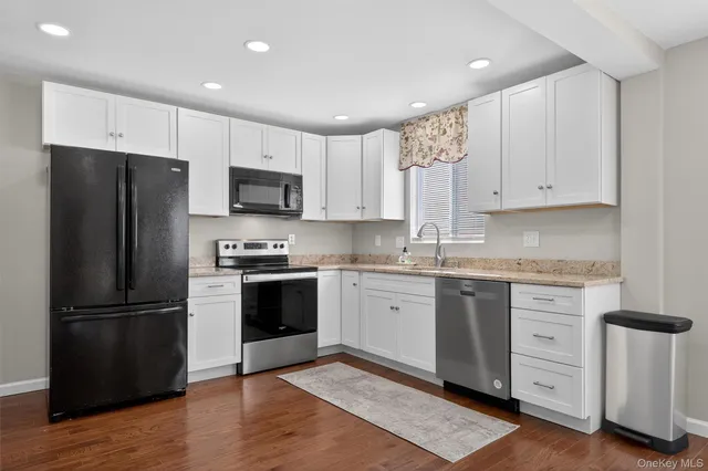 a kitchen with granite countertop white cabinets and stainless steel appliances