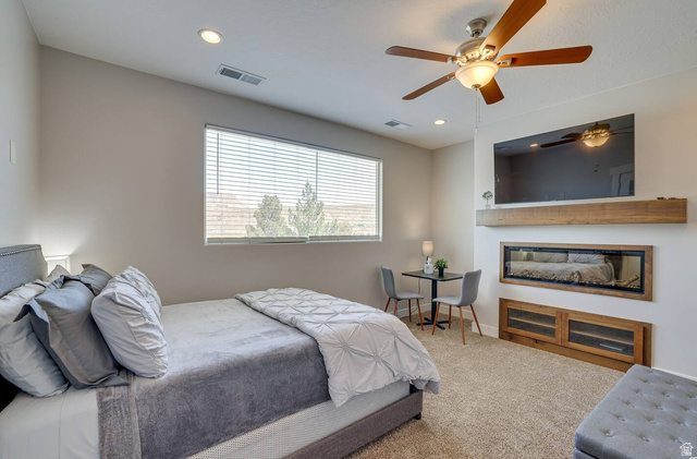 217 West Terrace Circle Toquerville, UT 84774 - Photo 5 of 25 Bedroom featuring carpet floors, recessed lighting, a ceiling fan, and a glass covered fireplace