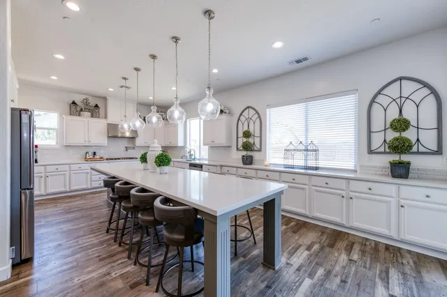 a large kitchen with stainless steel appliances a table chairs refrigerator microwave and cabinets