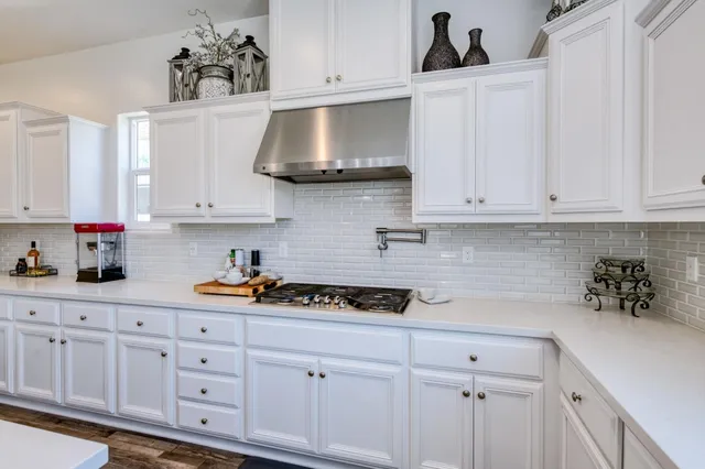 a kitchen with white cabinets and appliances