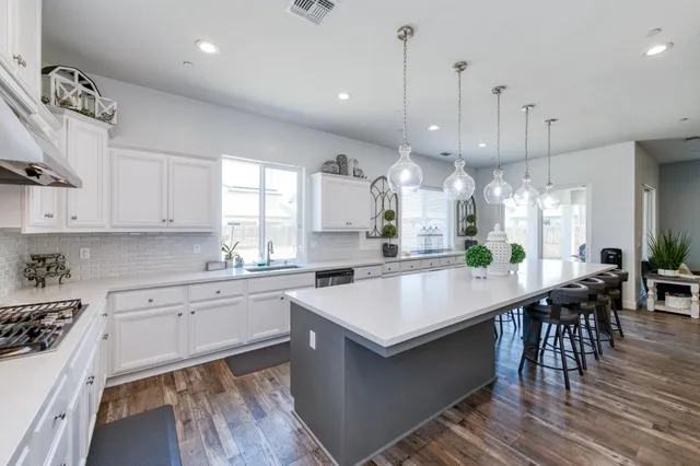 a large kitchen with kitchen island a dining table chairs and white cabinets