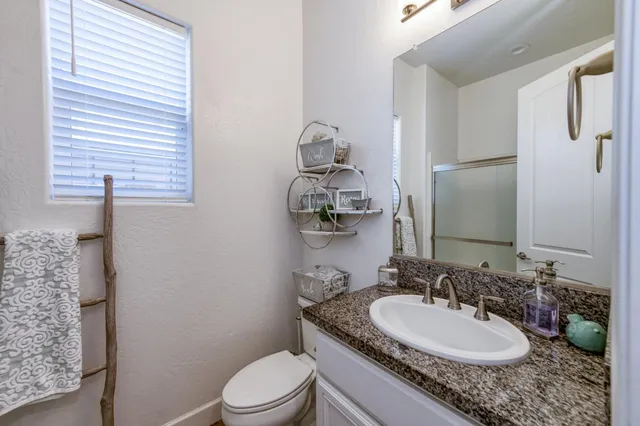 a bathroom with a granite countertop sink toilet and mirror