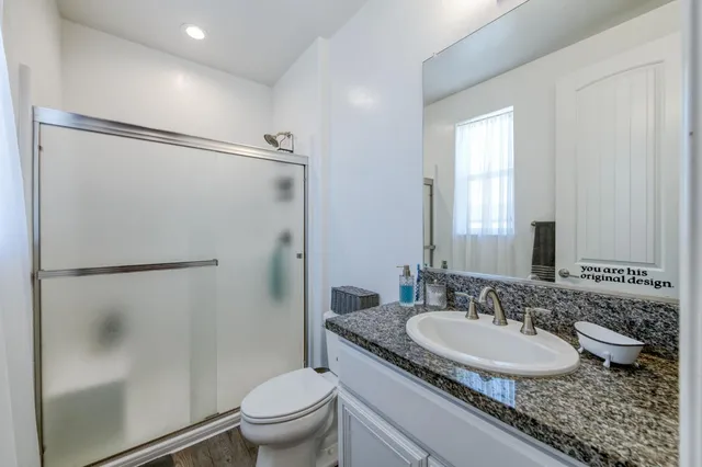 a bathroom with a granite countertop sink toilet and shower