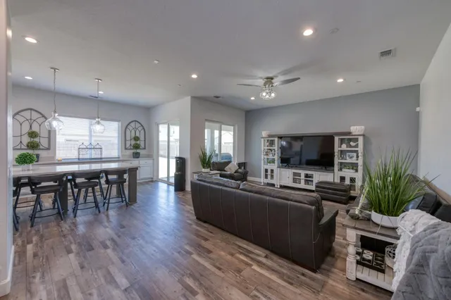 a living room with furniture a flat screen tv and a refrigerator
