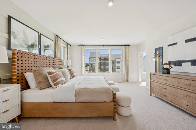 a spacious bedroom with a bed a table and painting on the wall