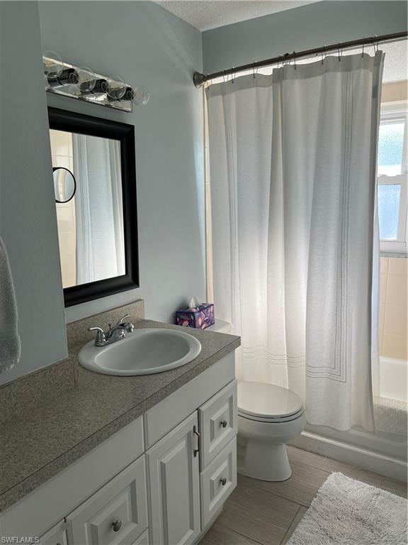 671 100th Avenue North Naples, FL 34108 - Photo 12 of 16 Full bathroom with shower / bath combo with shower curtain, a textured ceiling, vanity, and toilet