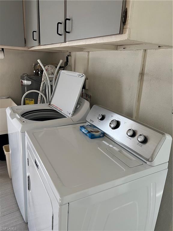 671 100th Avenue North Naples, FL 34108 - Photo 15 of 16 Laundry room featuring washer and clothes dryer, light tile patterned floors, and cabinets