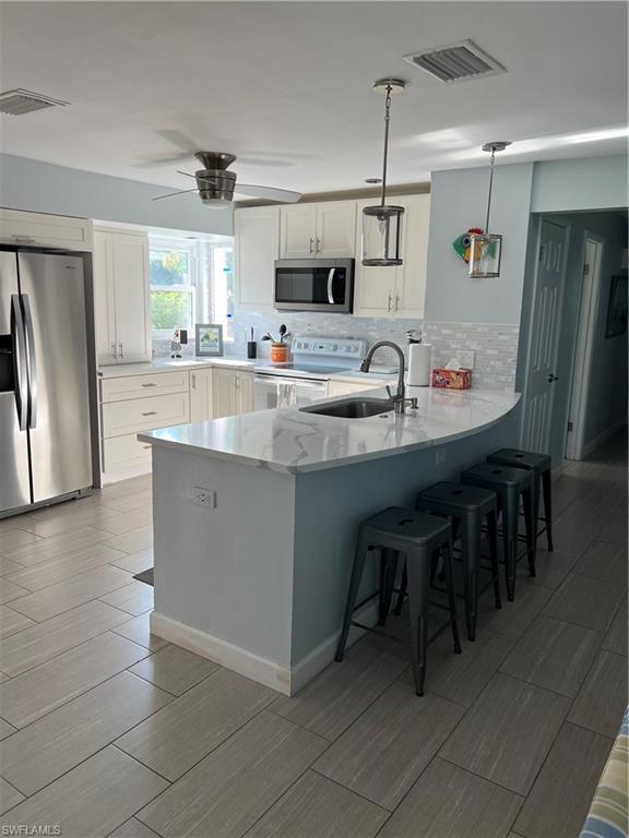671 100th Avenue North Naples, FL 34108 - Photo 3 of 16 Kitchen featuring decorative light fixtures, decorative backsplash, white range with electric stovetop, white cabinetry, and fridge
