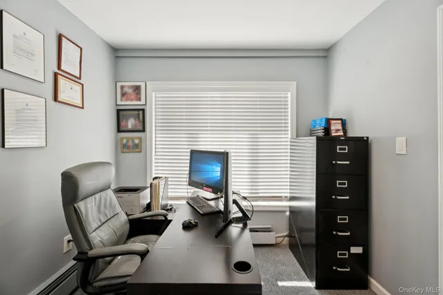 a view of a workspace with furniture and a window