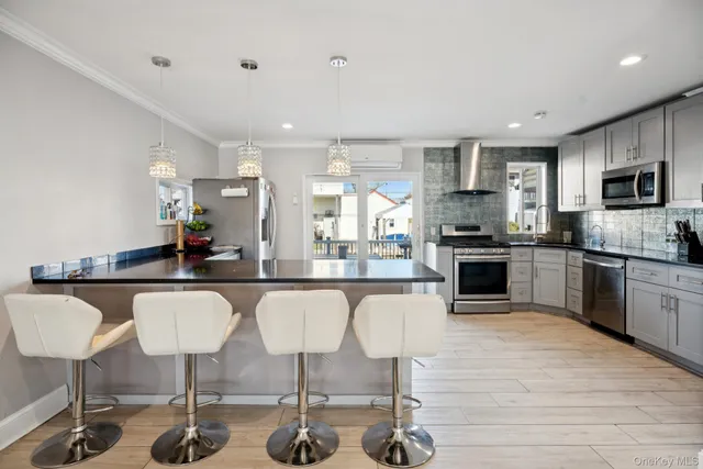 a kitchen with stainless steel appliances granite countertop a stove top oven a sink dishwasher a dining table and chairs with wooden floor