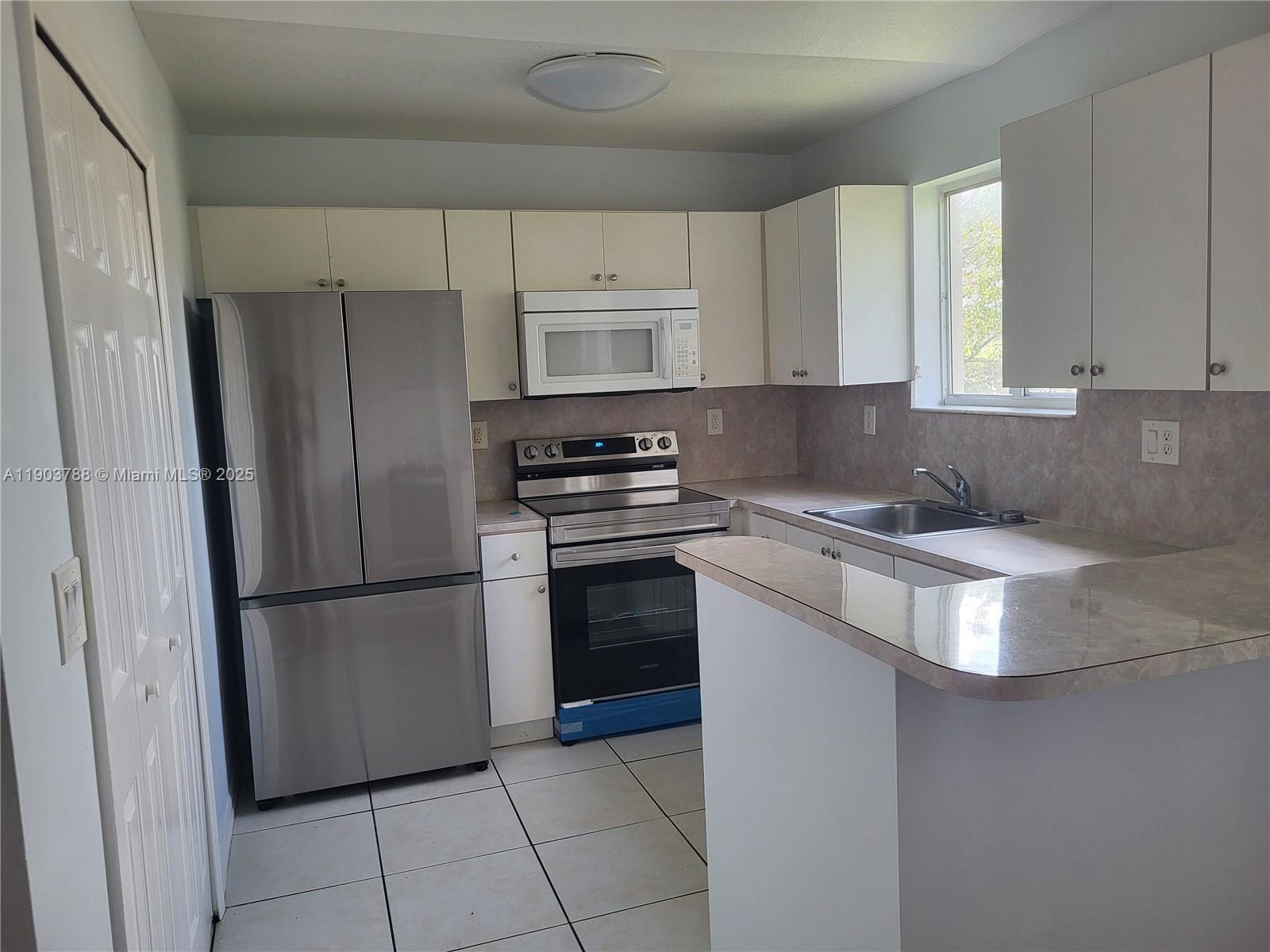 2920 Southeast 12th Road, Unit 20130 Homestead, FL 33035 - Photo 1 of 11 a kitchen with a refrigerator sink and cabinets