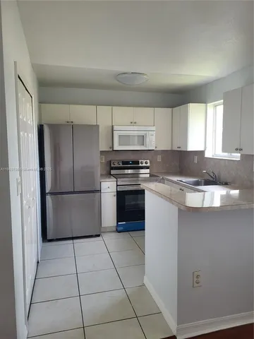 a kitchen with granite countertop a refrigerator and a sink