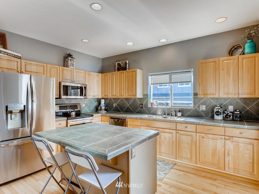 16624 Southeast 169th Street Renton, WA 98058 - Photo 8 of 21 a kitchen with stainless steel appliances a stove a sink a microwave a refrigerator and cabinets