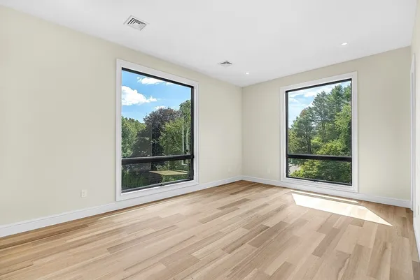 an empty room with wooden floor and windows