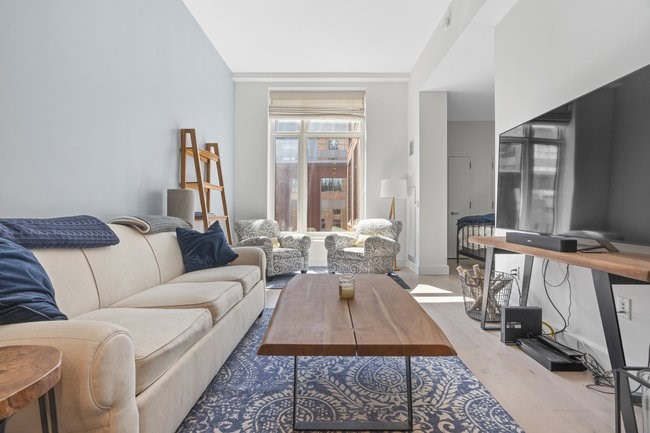100 Lovejoy Place, Unit 12Q Boston, MA 02114 - Photo 1 of 13 a living room with furniture a rug and a large window