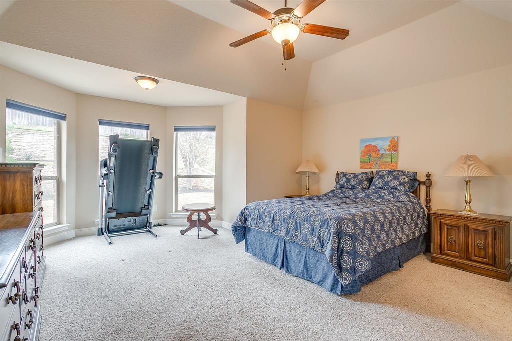9815 Ravenswood Road Granbury, TX 76049 - Photo 20 of 40 a spacious bedroom with a bed and a chandelier