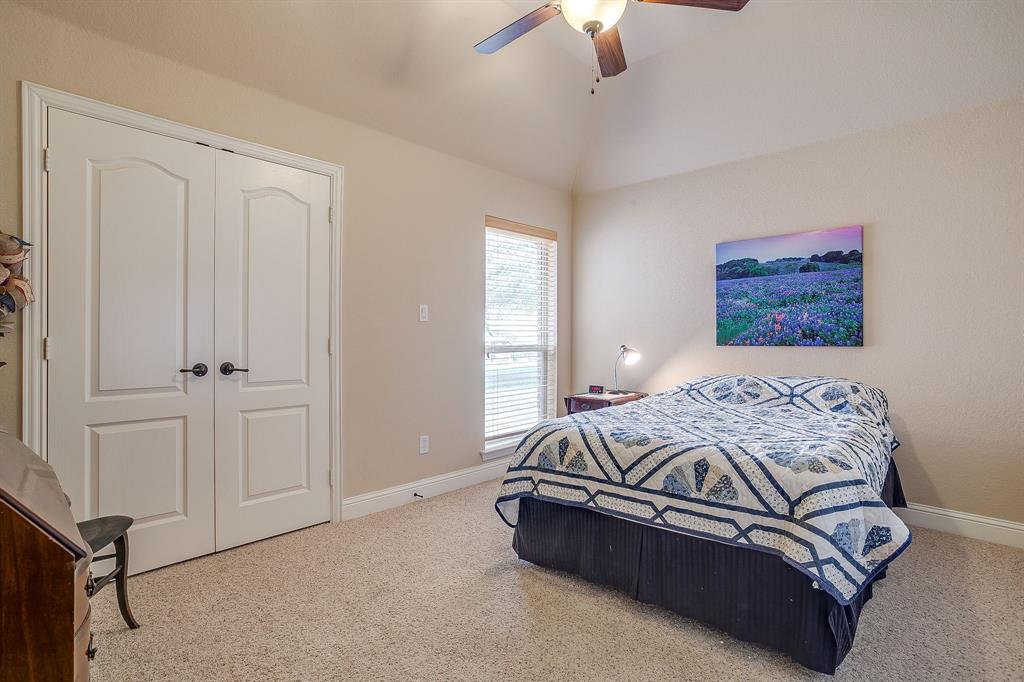 9815 Ravenswood Road Granbury, TX 76049 - Photo 29 of 40 a bedroom with a bed and a chandelier