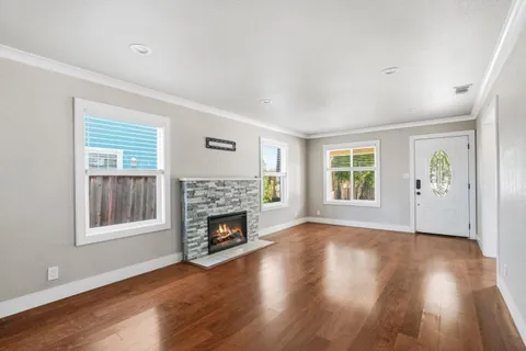 an empty room with windows a fireplace and wooden floor