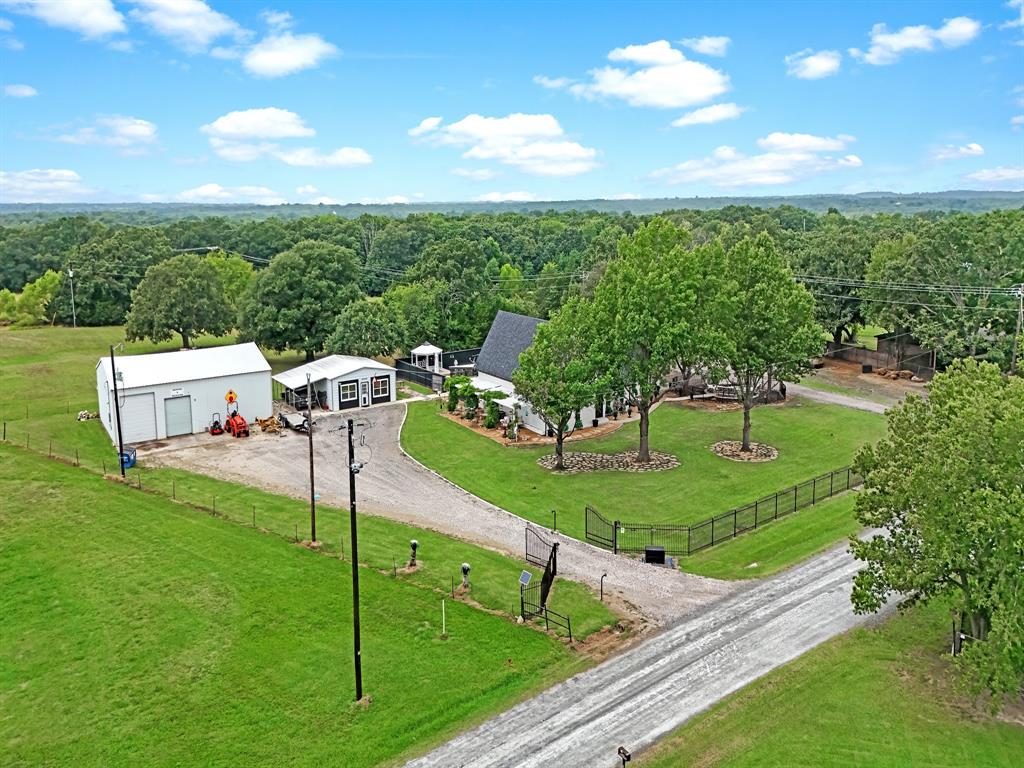 9867 Dripping Spring Road Denison, TX 75021 - Photo 7 of 40 Expansive property featuring a white residence with dark roof, a detached white garage with two bay doors, a secondary white structure with dark trim, and a decorative white gazebo